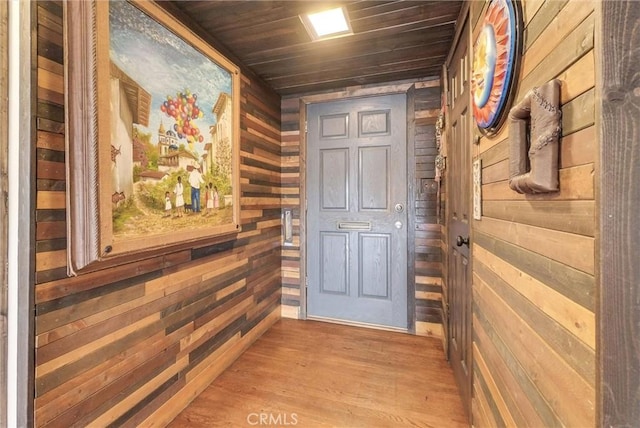 entryway featuring wood walls, light wood finished floors, and wood ceiling