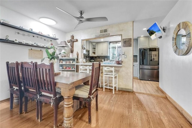 dining space featuring light wood-style floors, baseboards, a ceiling fan, and visible vents