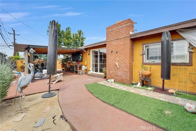 back of property featuring a patio, stucco siding, and a chimney