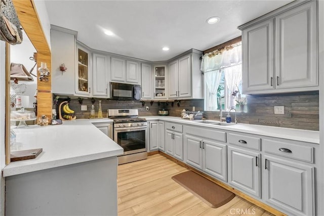 kitchen with gas range, a sink, black microwave, gray cabinetry, and backsplash