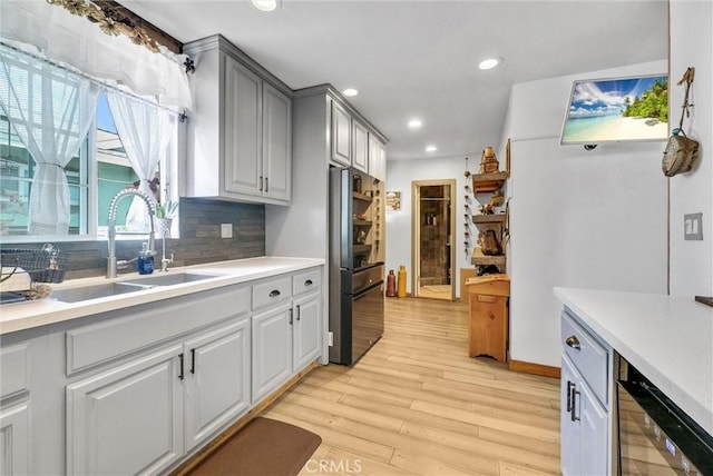 kitchen featuring light wood-style flooring, tasteful backsplash, recessed lighting, a sink, and light countertops