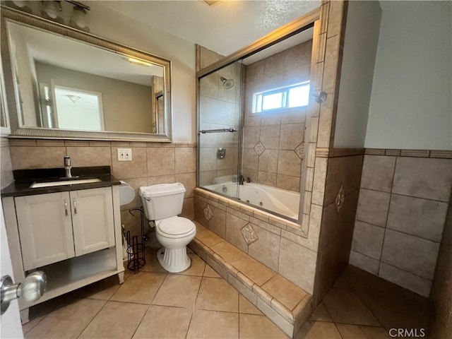 full bathroom featuring vanity, tile patterned floors, toilet, tiled shower / bath combo, and tile walls