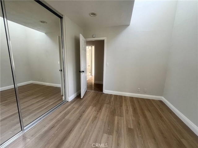 unfurnished bedroom featuring a closet, baseboards, and wood finished floors