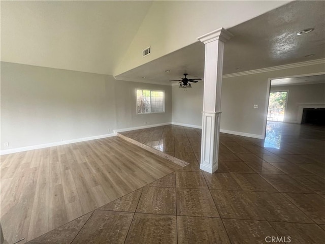 tiled spare room with crown molding, ceiling fan, a fireplace, ornate columns, and baseboards