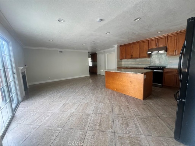 kitchen featuring freestanding refrigerator, crown molding, a kitchen island, under cabinet range hood, and electric stove