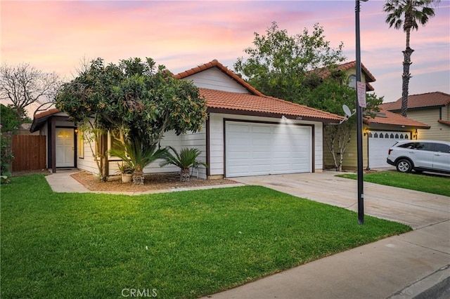 view of front of property with a lawn, a tiled roof, and a garage