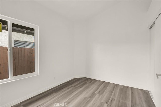 unfurnished room with baseboards and wood finished floors