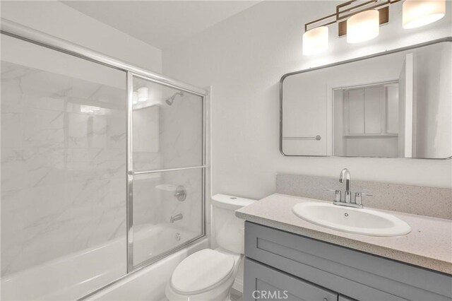 bathroom featuring bath / shower combo with glass door, toilet, and vanity