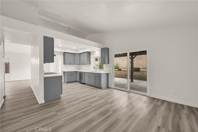 kitchen with vaulted ceiling, baseboards, light wood-style floors, gray cabinetry, and dishwasher