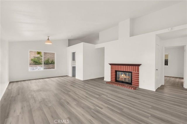 unfurnished living room featuring vaulted ceiling, wood finished floors, and a fireplace