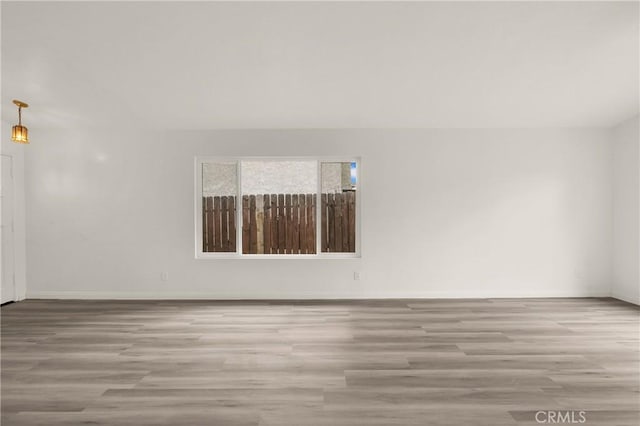 spare room with baseboards and wood finished floors