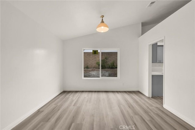 spare room featuring baseboards, lofted ceiling, visible vents, and light wood-style flooring