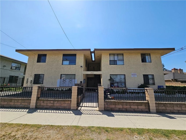 view of front of property with a fenced front yard, stucco siding, and a gate