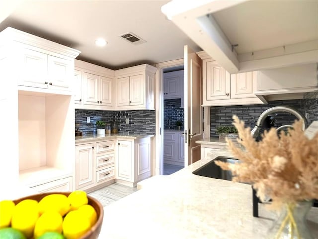 kitchen featuring tasteful backsplash, recessed lighting, white cabinets, light stone countertops, and visible vents