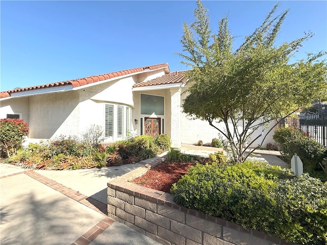 view of front of property featuring stucco siding, fence, and a tile roof
