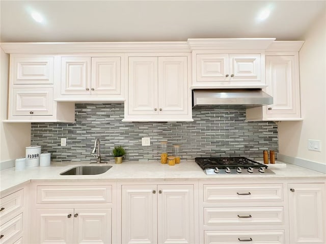 kitchen featuring a sink, wall chimney range hood, light countertops, and stainless steel gas stovetop