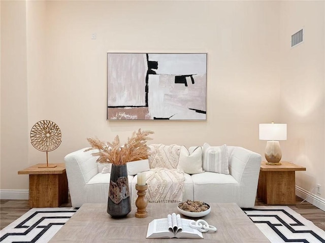 living room featuring visible vents, baseboards, and wood finished floors
