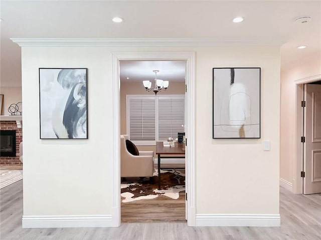 hall with baseboards, light wood-type flooring, an inviting chandelier, ornamental molding, and recessed lighting