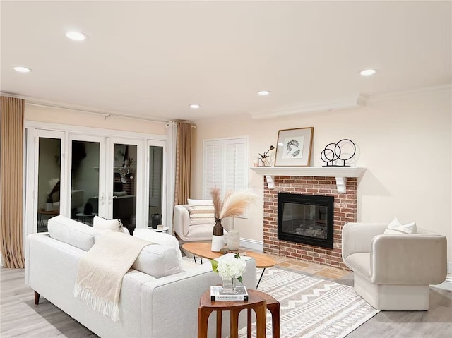 living area featuring light wood-style flooring, ornamental molding, a brick fireplace, and recessed lighting
