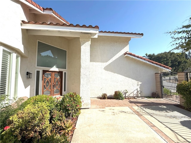 doorway to property with stucco siding, a gate, and a tile roof