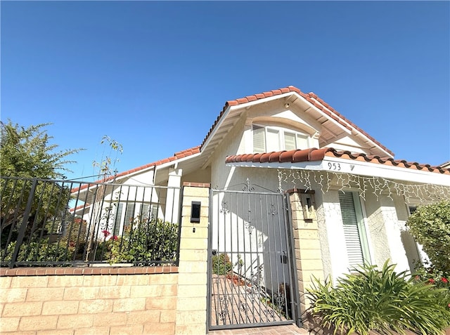 mediterranean / spanish-style house featuring a tiled roof, fence, and a gate