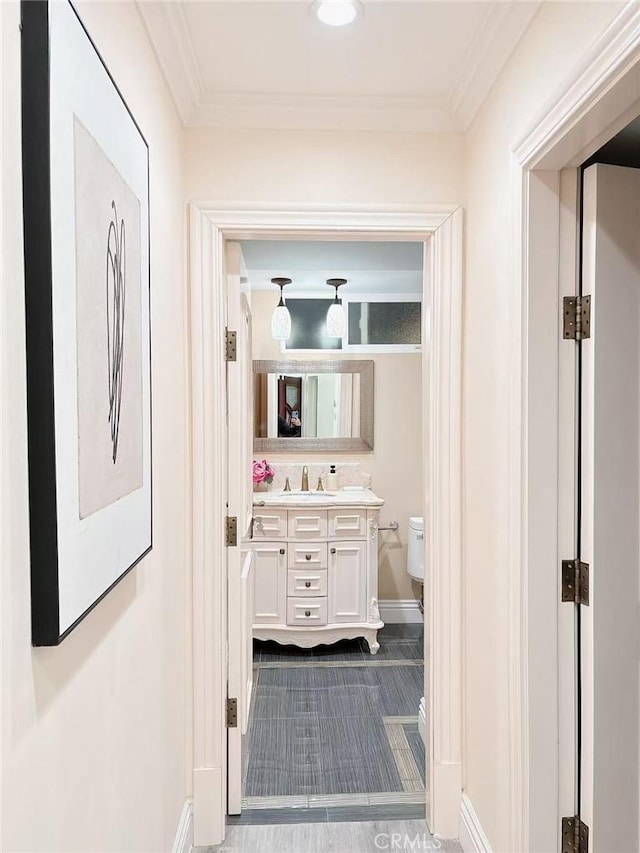 bathroom with vanity, baseboards, ornamental molding, and toilet
