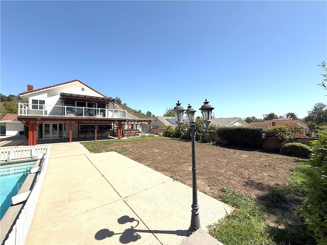 back of house featuring stairway, a patio, fence, a chimney, and a fenced in pool