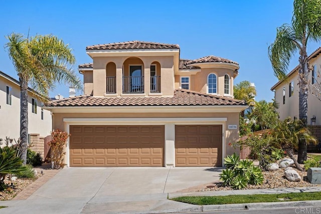 mediterranean / spanish home featuring concrete driveway, stucco siding, an attached garage, and a tile roof