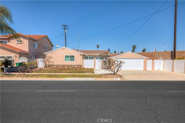 ranch-style house with driveway, fence, a garage, and stucco siding