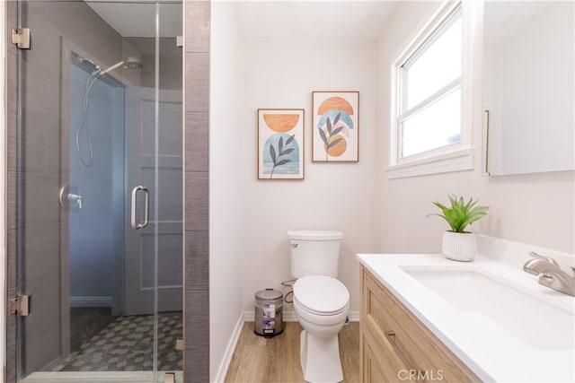 bathroom with toilet, a shower stall, vanity, and wood finished floors