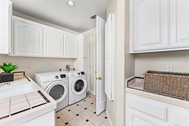 washroom featuring light floors, independent washer and dryer, visible vents, baseboards, and cabinet space