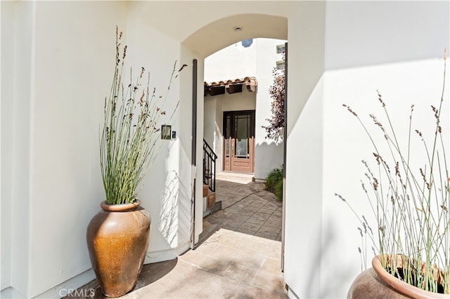 view of exterior entry featuring a tiled roof and stucco siding