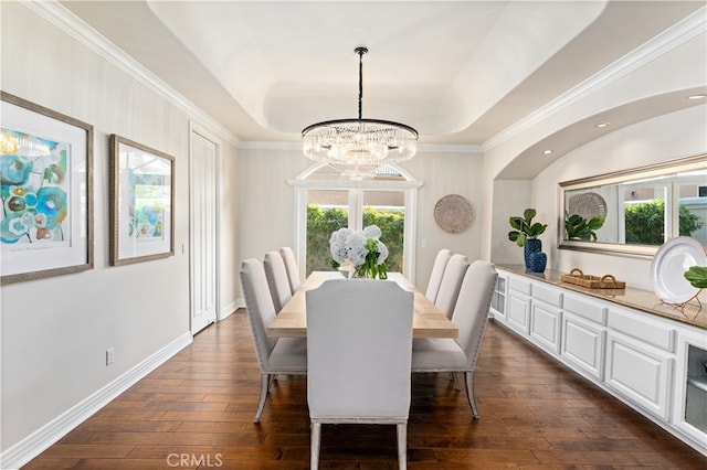 dining space with dark wood-style flooring, a tray ceiling, an inviting chandelier, and ornamental molding