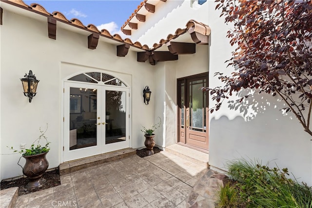 property entrance with french doors, stucco siding, and a tile roof