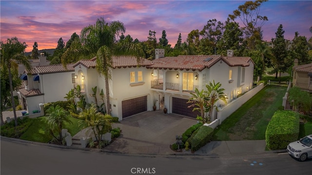 mediterranean / spanish-style house featuring a balcony, stucco siding, driveway, an attached garage, and a tile roof
