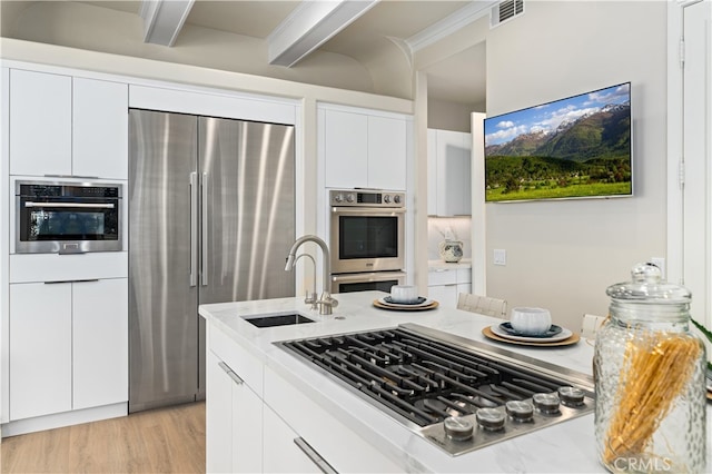 kitchen featuring visible vents, modern cabinets, a sink, appliances with stainless steel finishes, and light stone counters