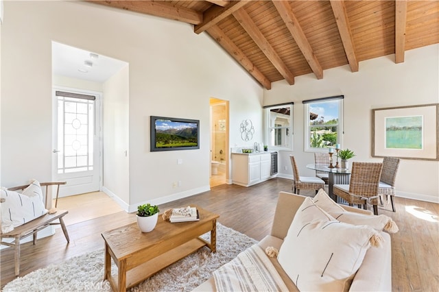 living area with baseboards, light wood-style floors, beam ceiling, high vaulted ceiling, and wooden ceiling