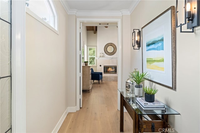 corridor with light wood finished floors, visible vents, baseboards, and ornamental molding
