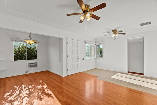 unfurnished living room featuring ornamental molding, a ceiling fan, visible vents, a wall mounted AC, and baseboards