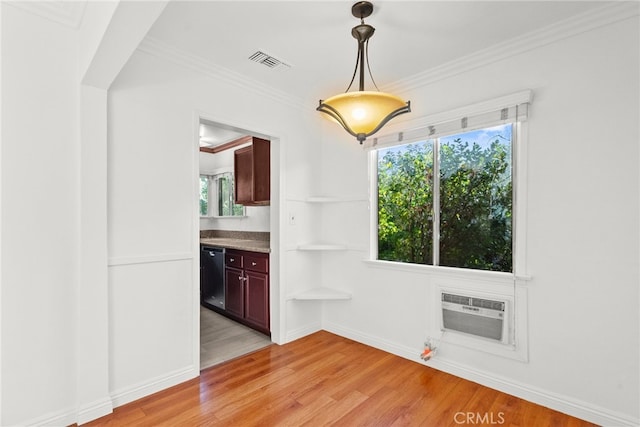 unfurnished dining area featuring visible vents, baseboards, ornamental molding, an AC wall unit, and light wood-style floors