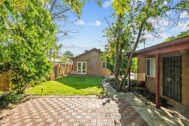 rear view of property featuring a yard, a fenced backyard, stucco siding, a patio area, and french doors