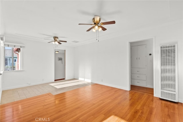 unfurnished living room featuring crown molding, a ceiling fan, a heating unit, and light wood-style floors