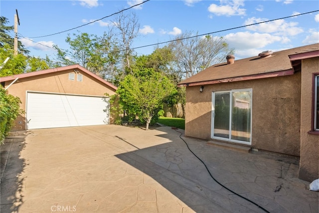exterior space featuring a detached garage, an outdoor structure, and stucco siding