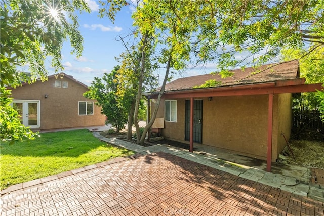 back of property with a patio, french doors, stucco siding, and a yard