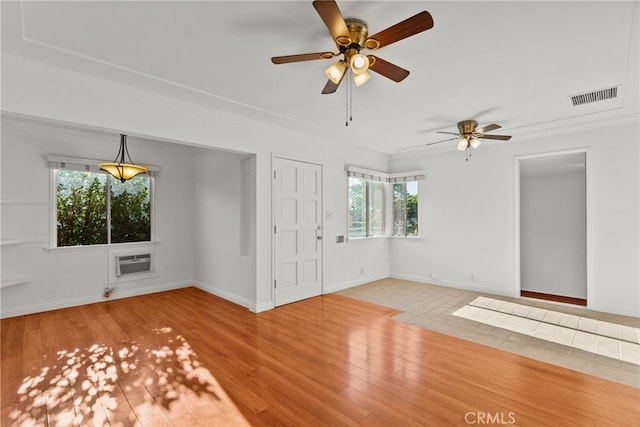 unfurnished living room featuring ceiling fan, ornamental molding, visible vents, a wall mounted air conditioner, and baseboards