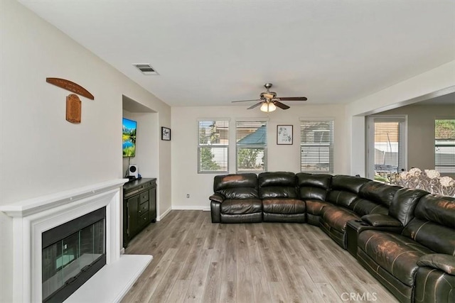 living area featuring a healthy amount of sunlight, visible vents, light wood-style flooring, and ceiling fan