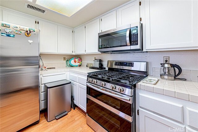 22933 Estoril Dr Unit 1, Diamond Bar, CA 91765 - kitchen with visible vents, white cabinets, light wood-style floors, tile counters, and stainless steel appliances