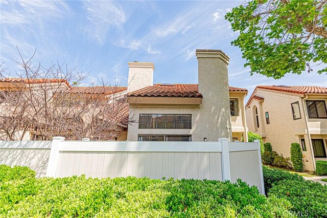 22933 Estoril Dr Unit 1, Diamond Bar, CA 91765 - back of property with a chimney, stucco siding, fence, and a tile roof