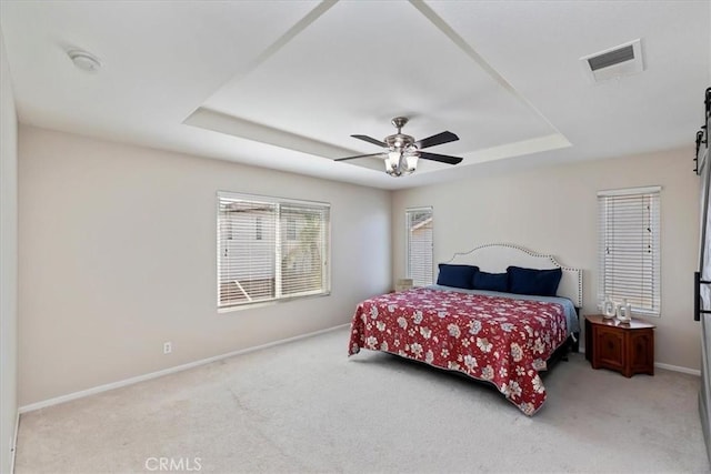 bedroom featuring visible vents, baseboards, a ceiling fan, carpet, and a tray ceiling