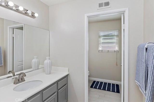 bathroom with toilet, visible vents, baseboards, and vanity